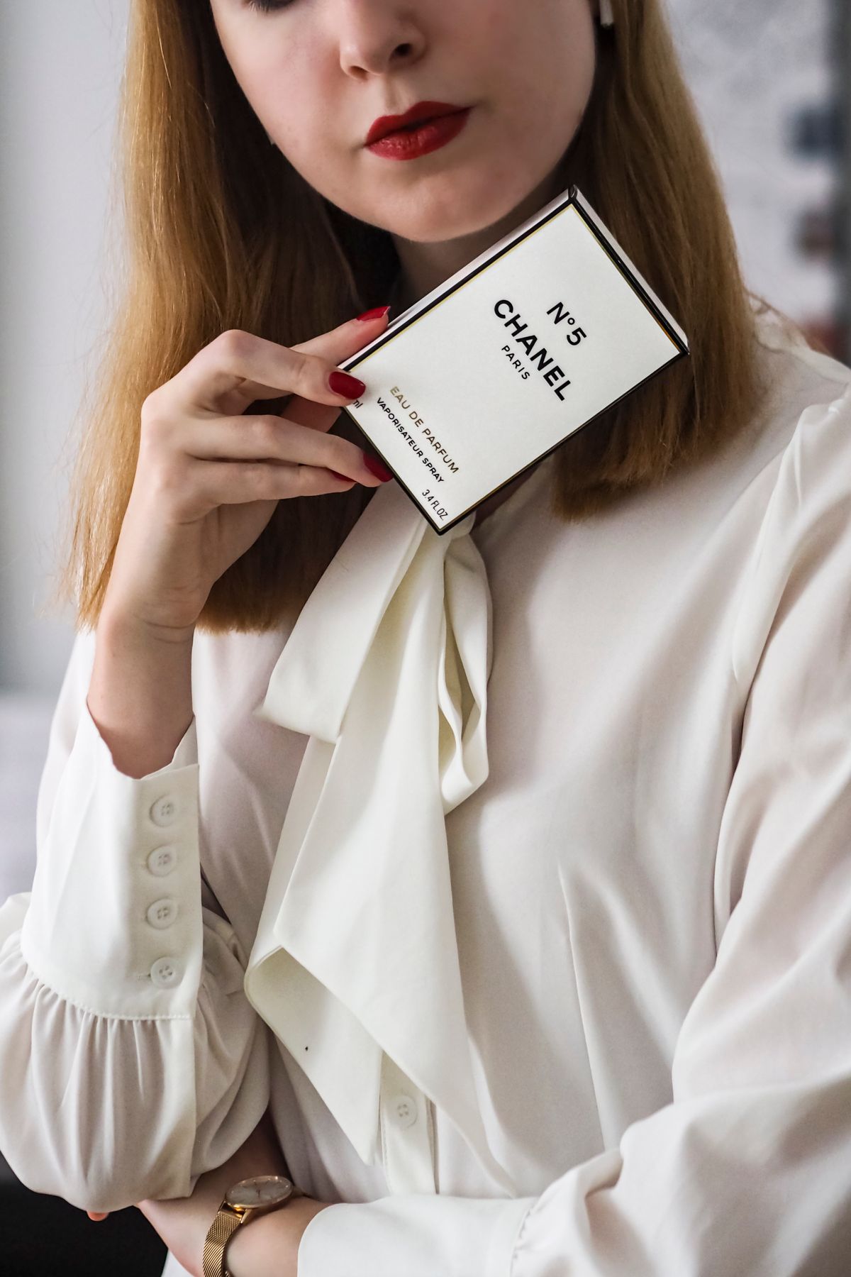 Sophisticated woman holding perfume box, showcasing elegance and luxury.